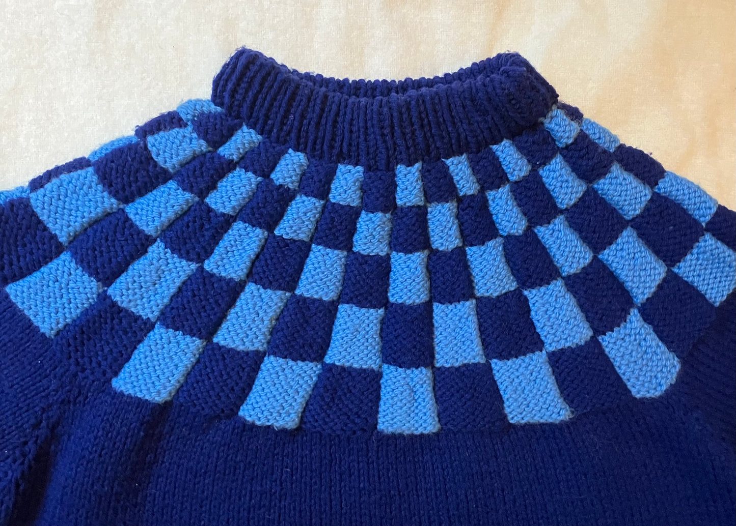 Vintage blue handknitted wool jumper with chequerboard pattern.