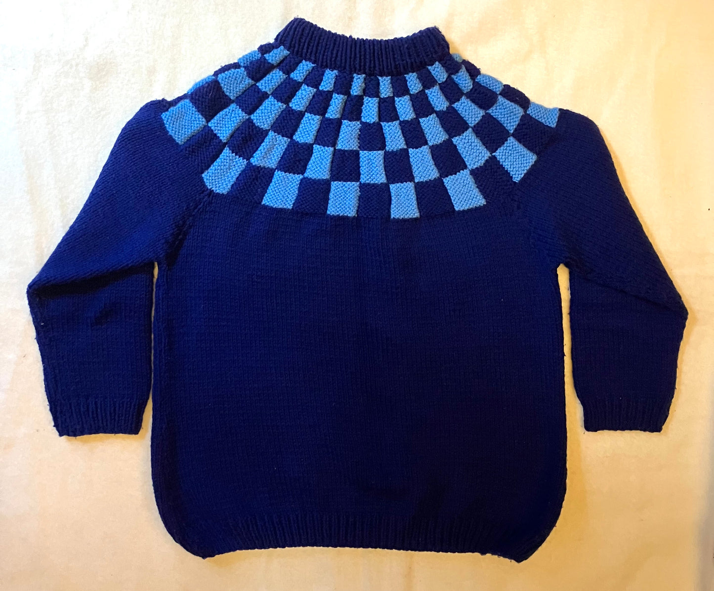 Vintage blue handknitted wool jumper with chequerboard pattern.